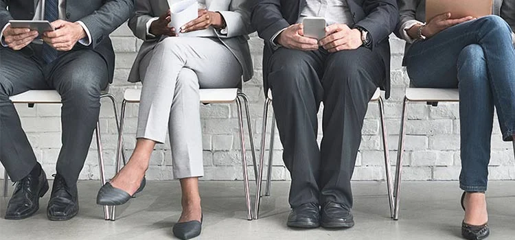 A varied group of people awaiting their turn in a job interview.