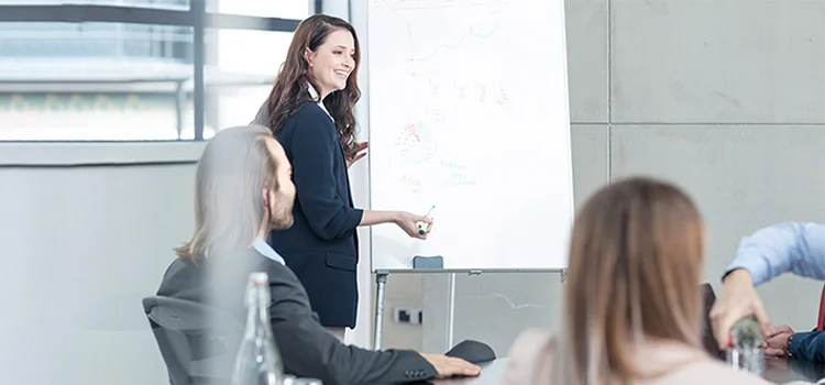 A lady is delivering a formal presentation at a meeting in a conference room