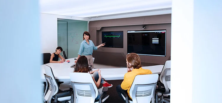 Lady presenting on a screen at a meeting conference in an office setting.